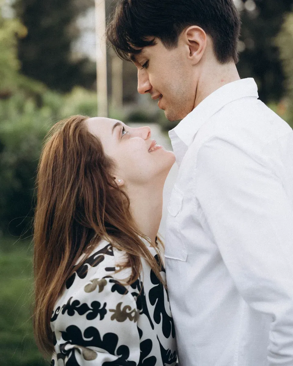 A couple in white, foreheads almost touching, laughing.