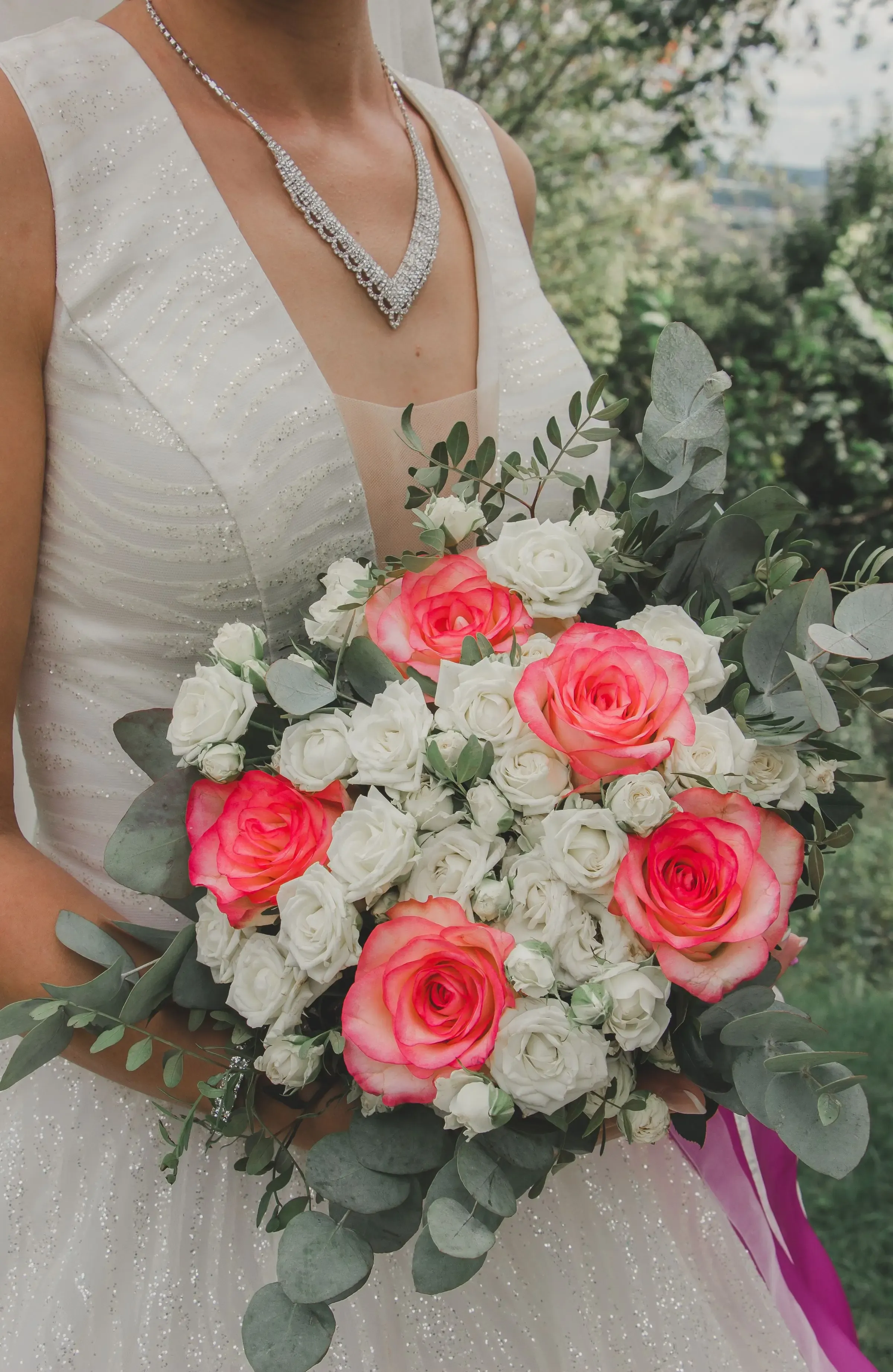 Bride in a white dress holding a bouquet of pink and white roses.
