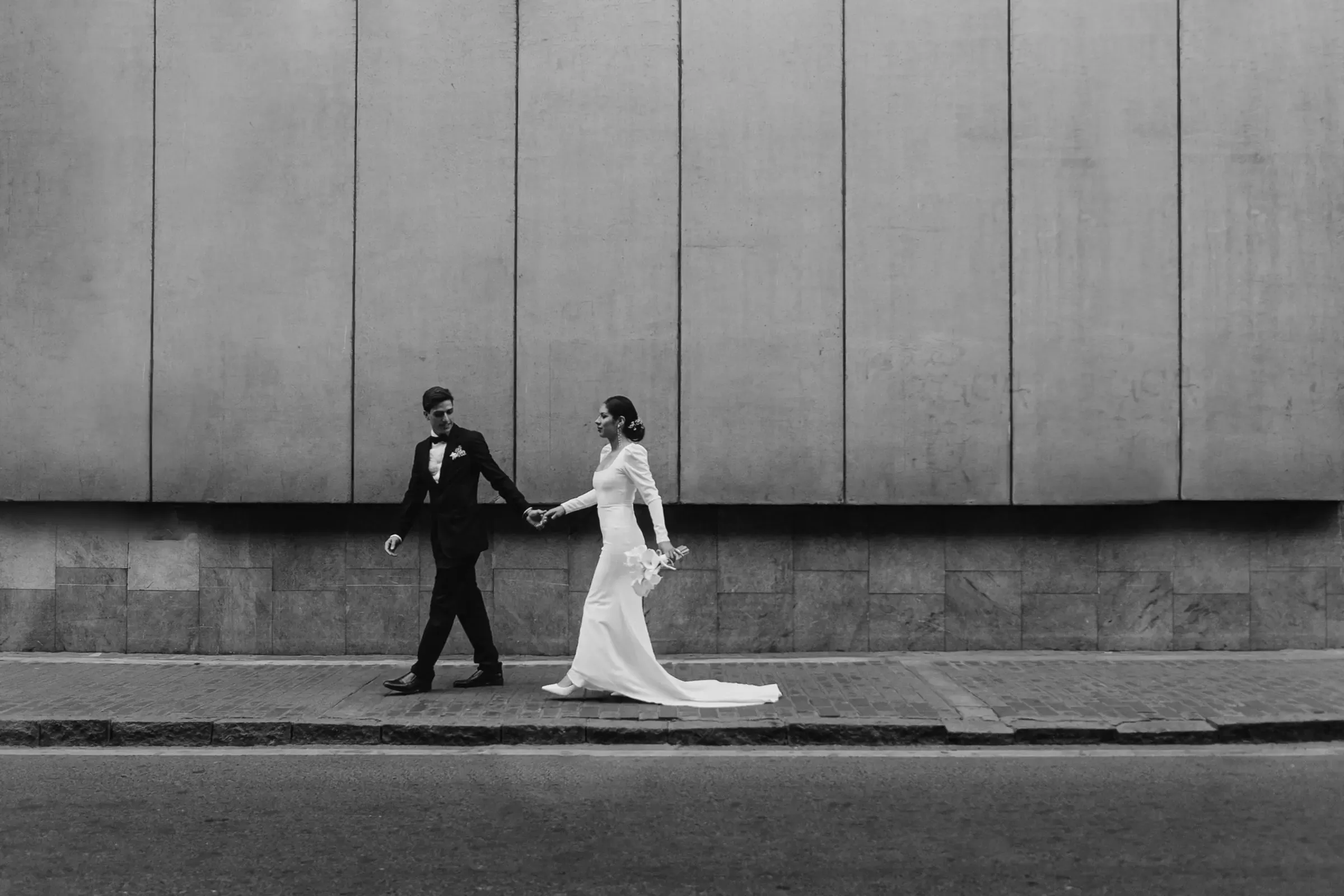 Bride and groom walking along a city street in Lima, in black and white.