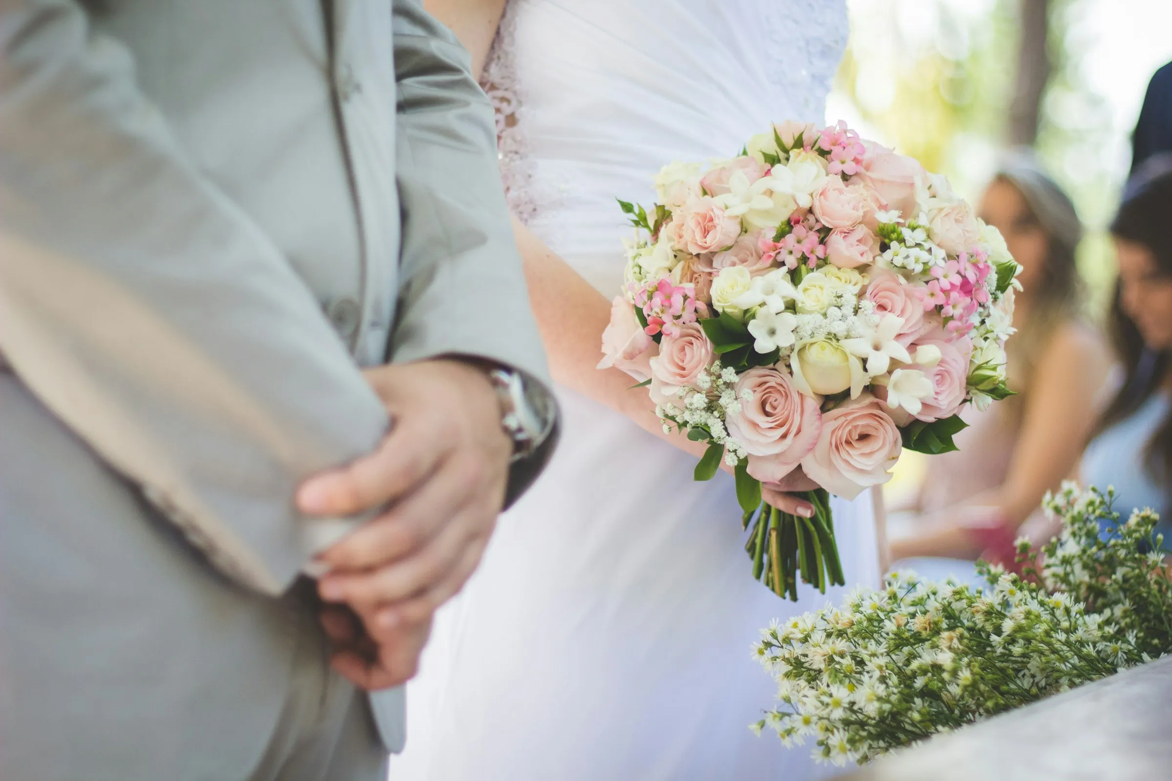Bride and groom embracing beneath sunlit stone arches.
