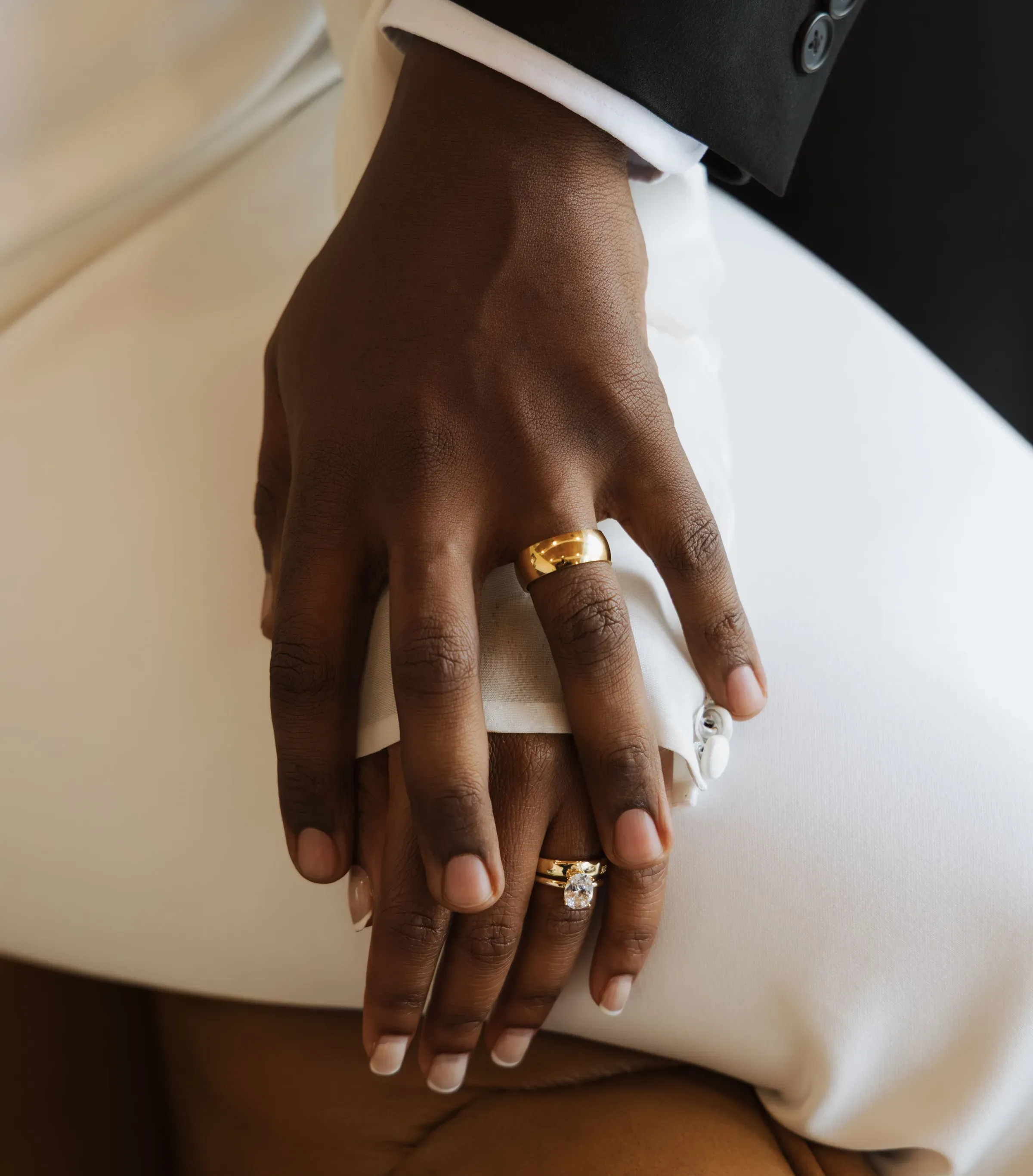 The couple's hands laid together, both wearing gold wedding rings.
