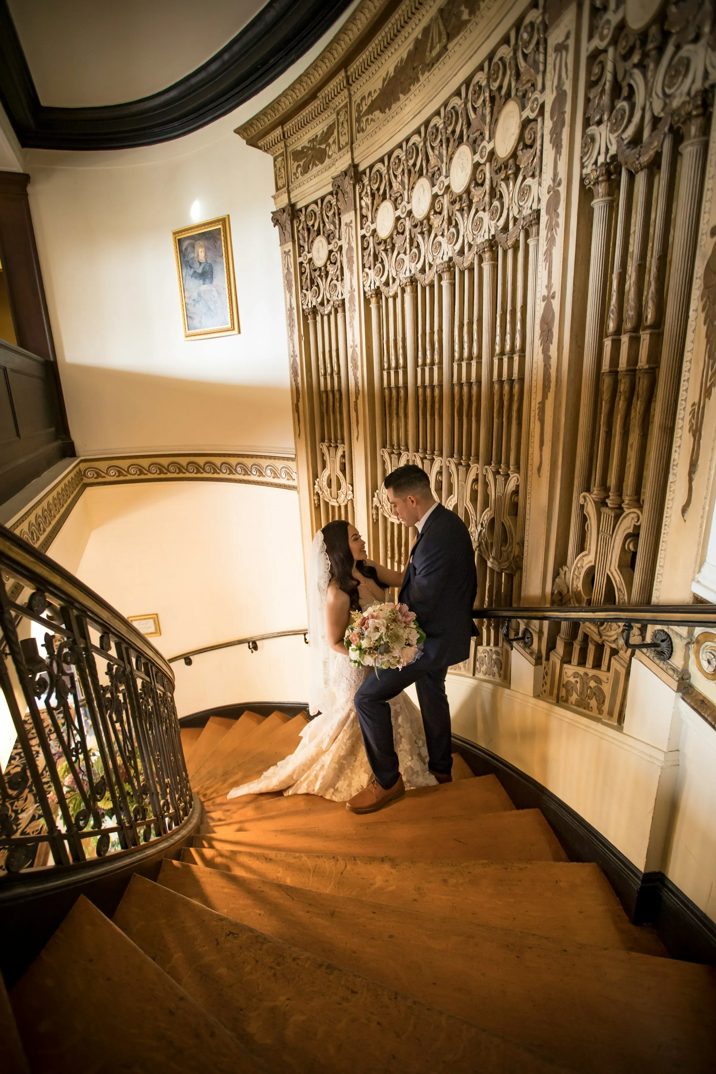 Bride and groom sitting together on stone steps outside a historic building.