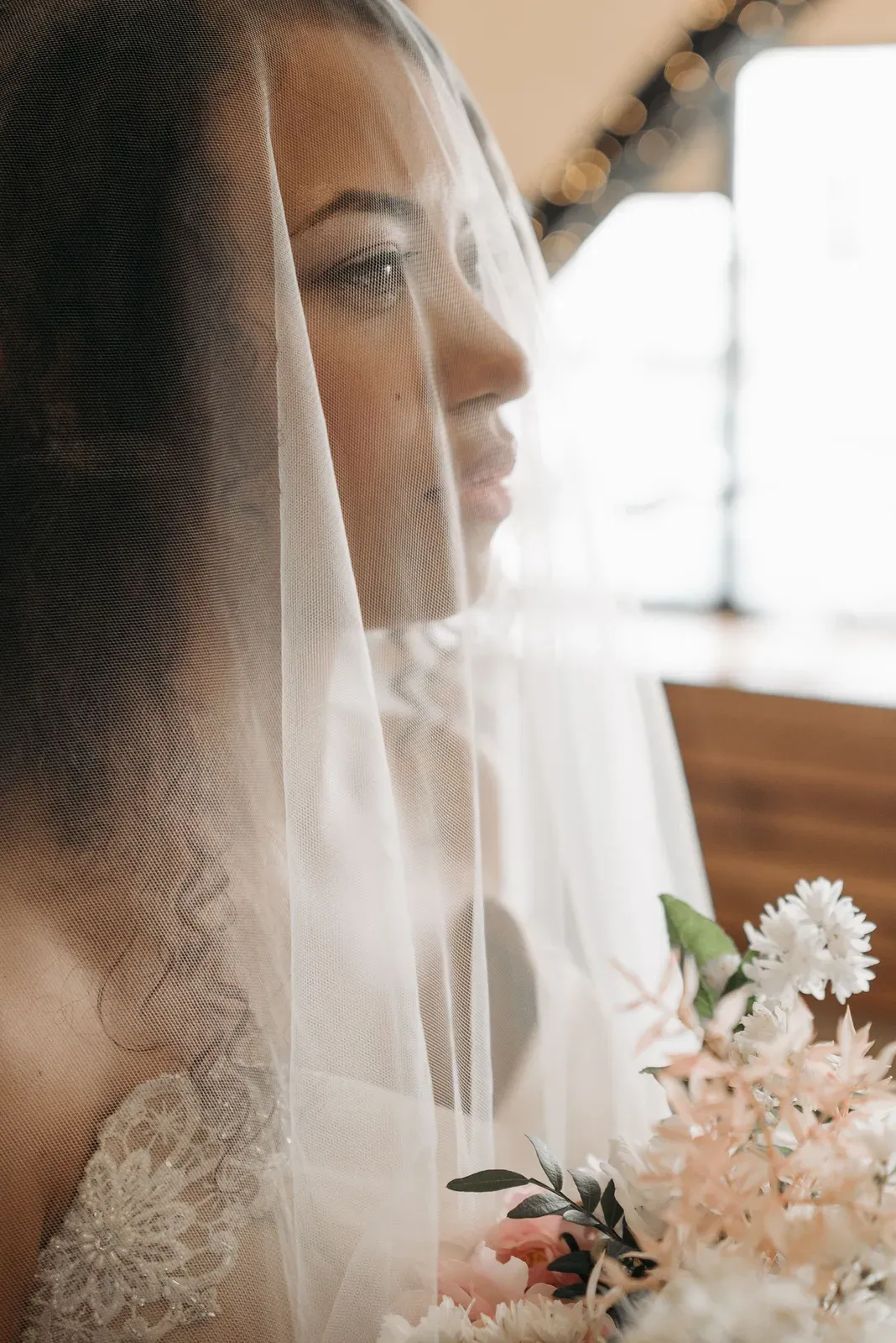 The bride seen through her veil, white flowers soft in the foreground.
