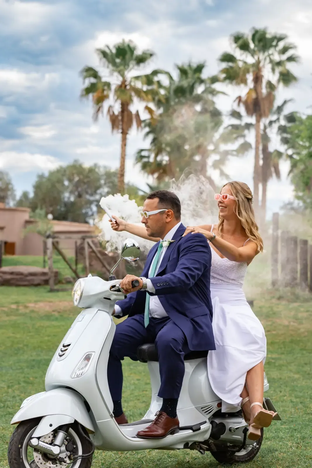 Happy couple celebrating wedding day riding a scooter, joyfully outdoors.