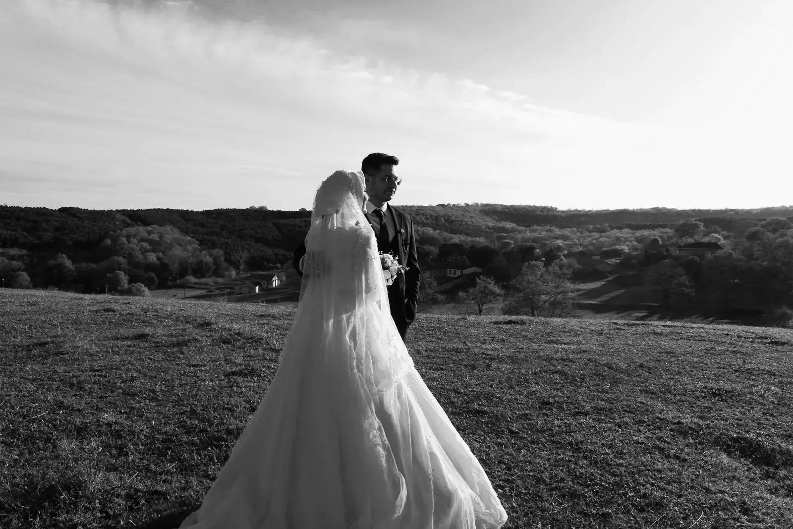 Bride and groom among rolling hills, in black and white.