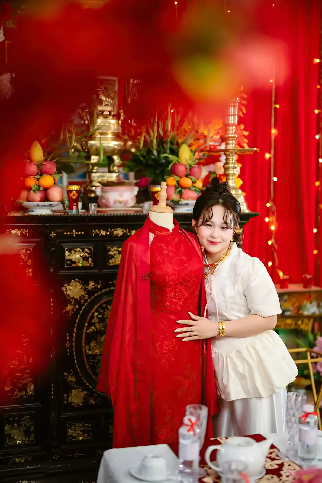 Traditional Vietnamese wedding setup with a woman in vibrant attire embracing a traditional dress display.