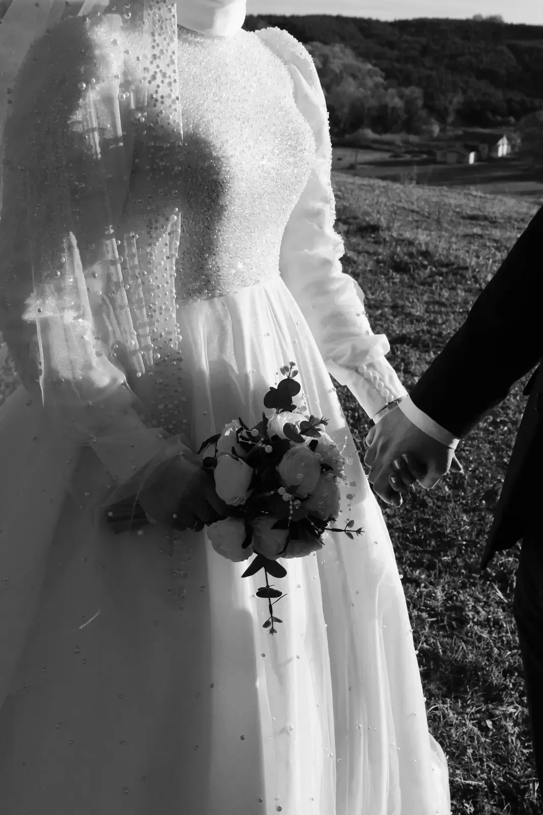 Bride and groom holding hands outdoors, in black and white.