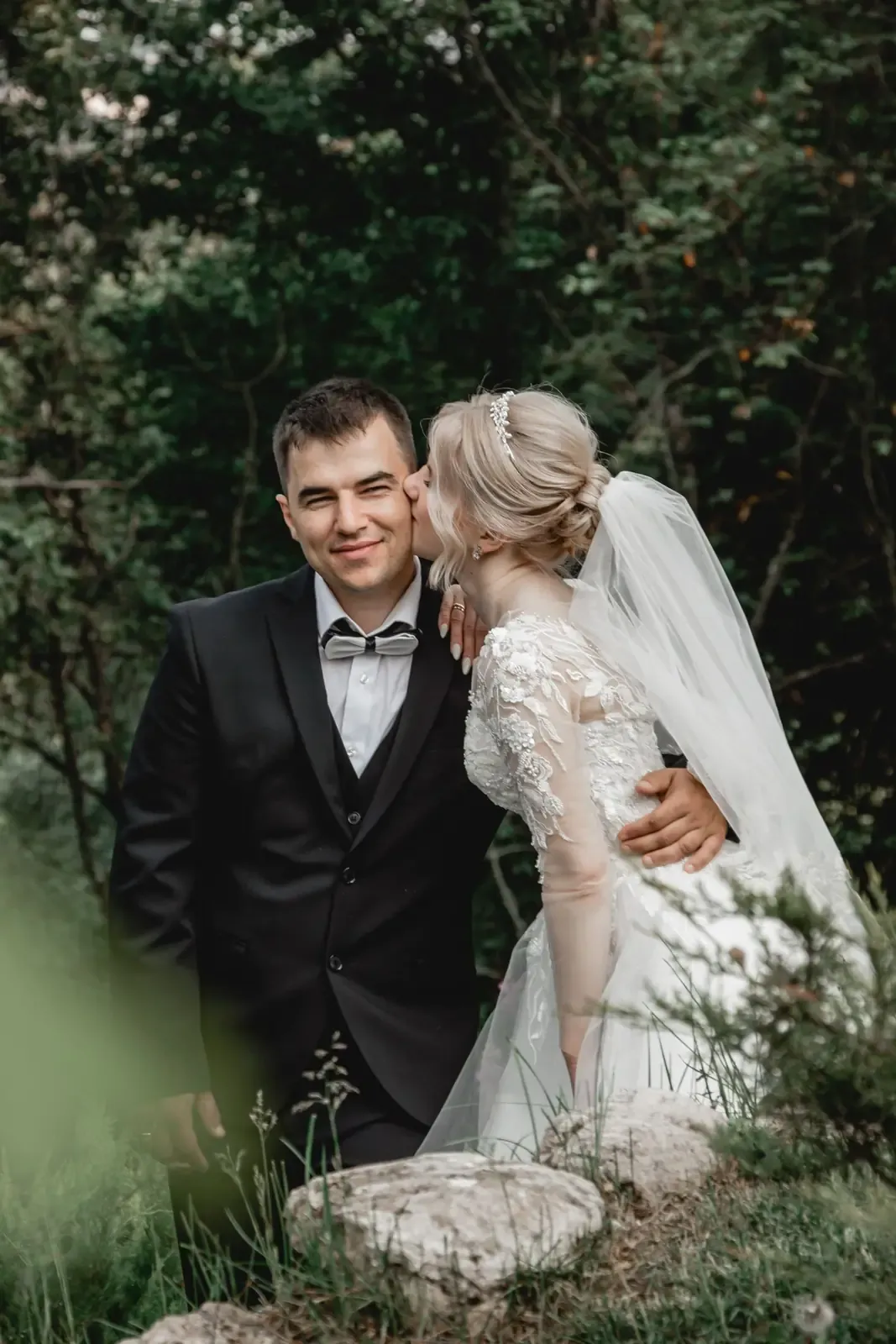 Bride kissing groom in a romantic outdoor wedding portrait.