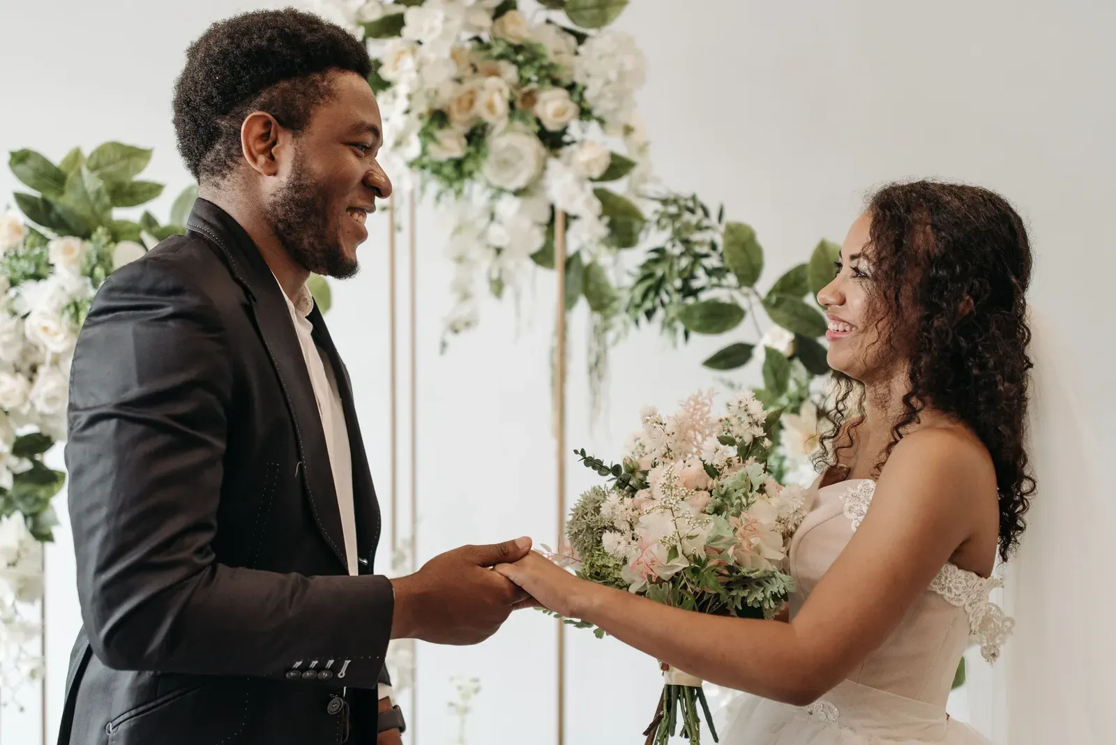 The groom laughing as he takes the bride's hands in his.