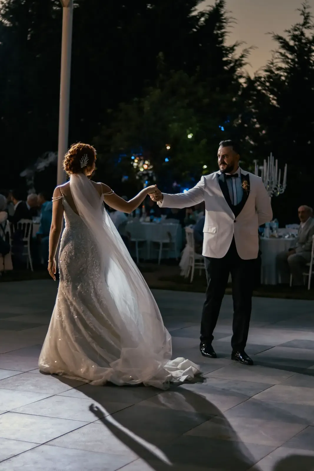 Stylish couple shares a graceful dance under the night sky during a romantic wedding celebration.