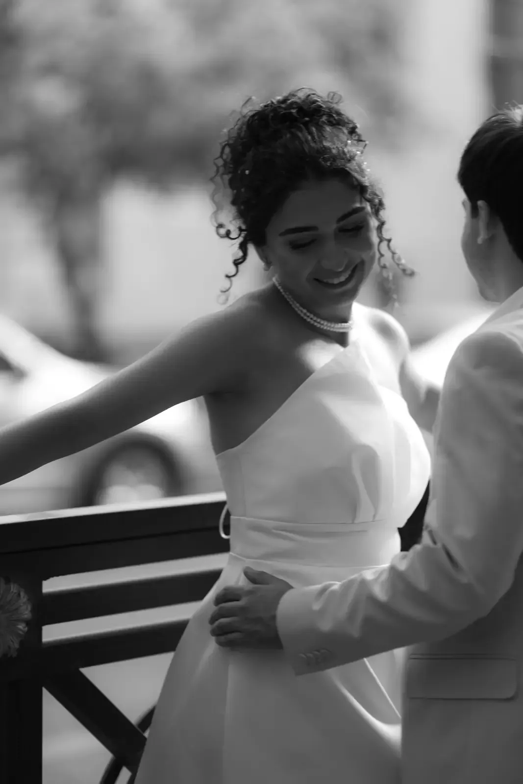 A bride and groom laughing together, in black and white.