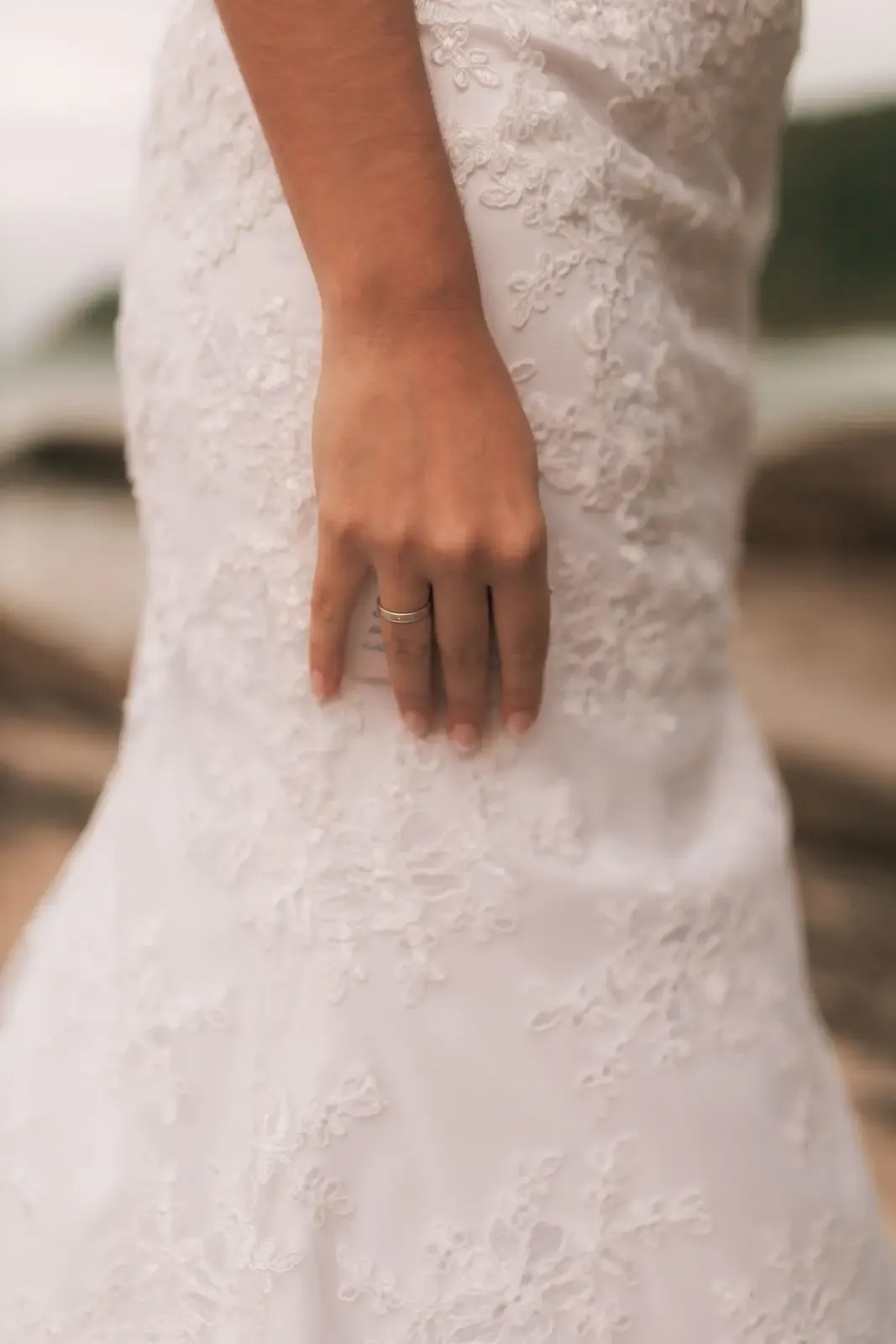 Close-up of a bride's hand with an elegant ring, holding a white rose bouquet.
