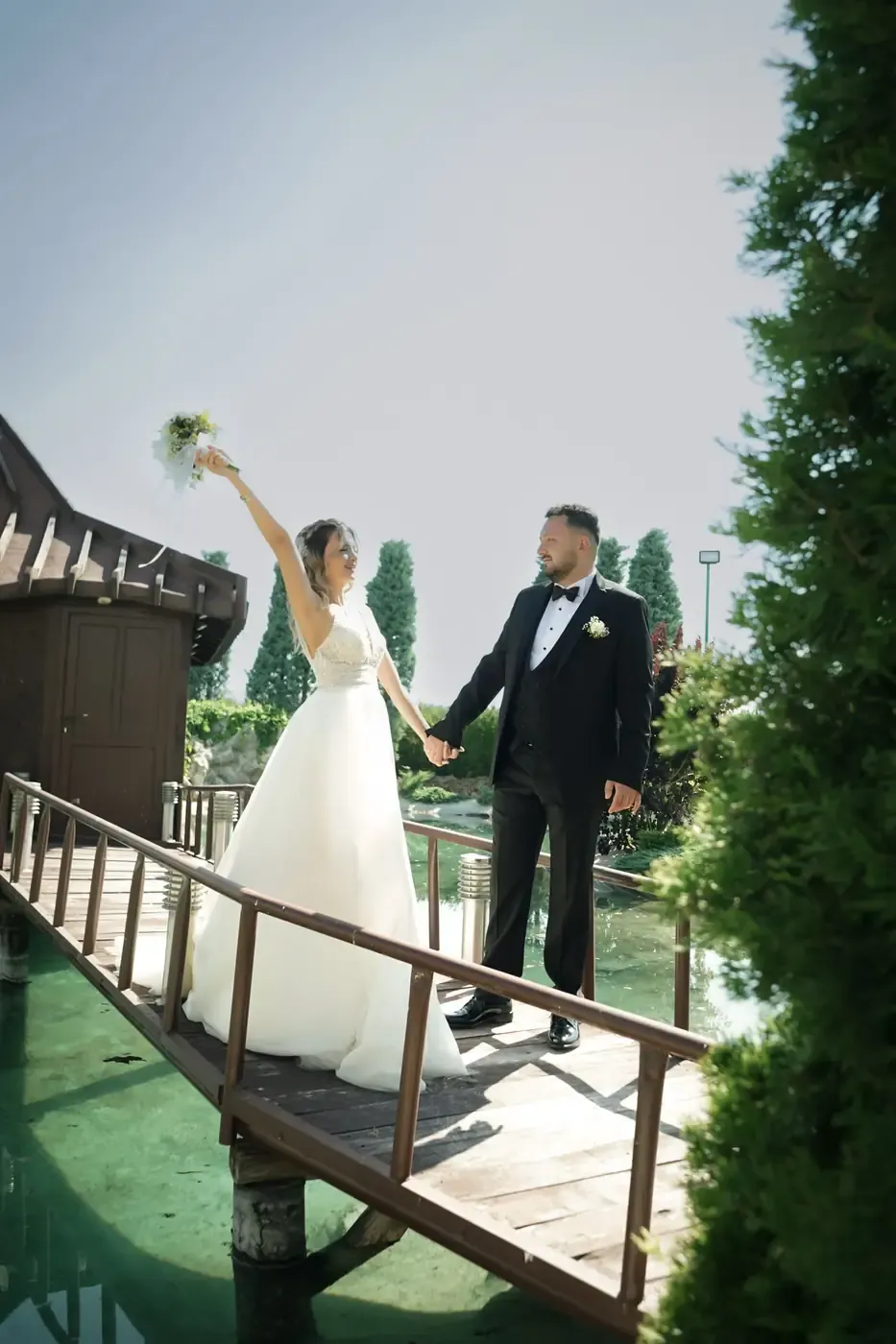 Bride and groom celebrating their wedding on a picturesque wooden bridge.