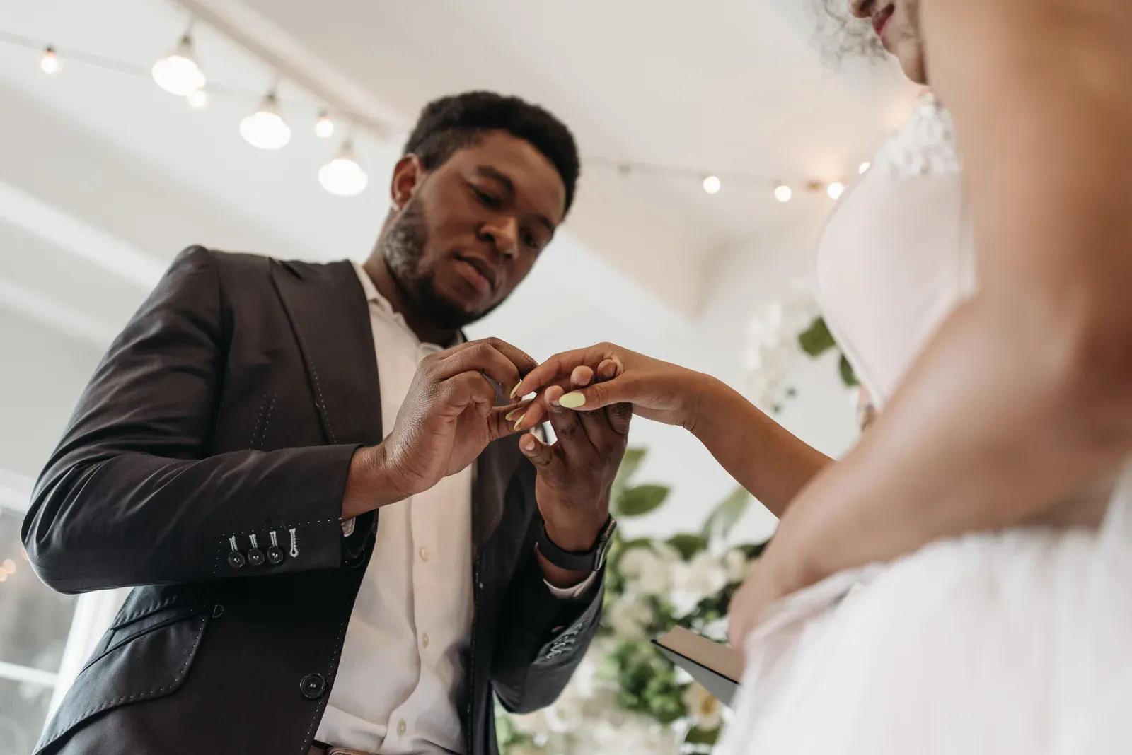 The groom sliding the ring onto the bride's finger.