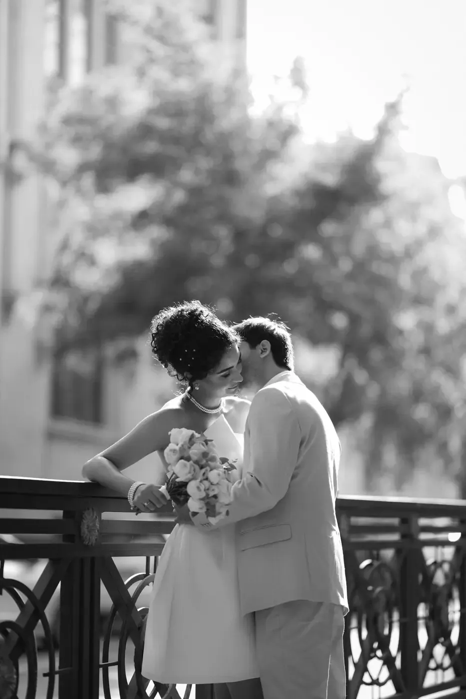 A couple kissing on their wedding day, in black and white.