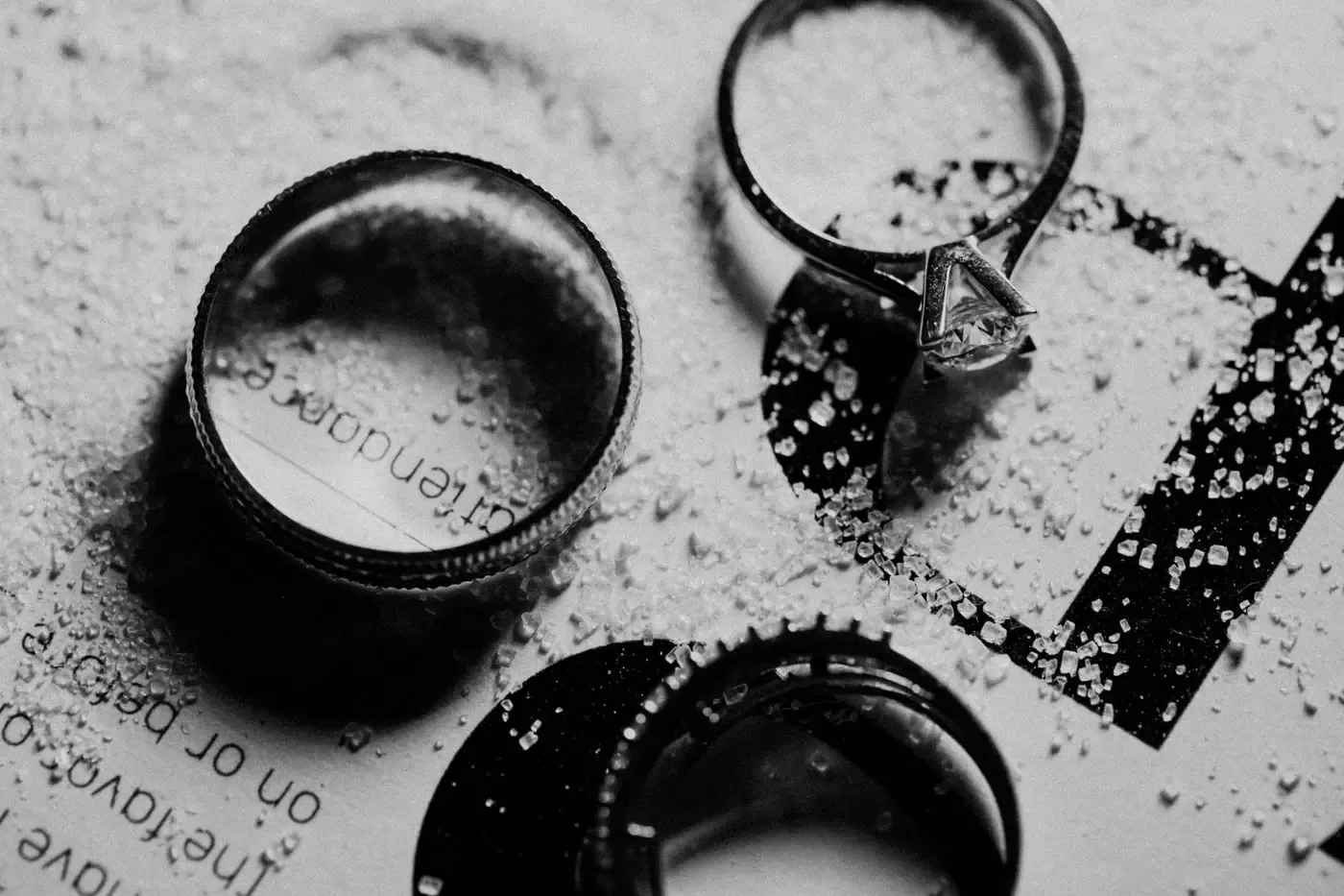Engagement and wedding rings on a textured surface, in black and white.