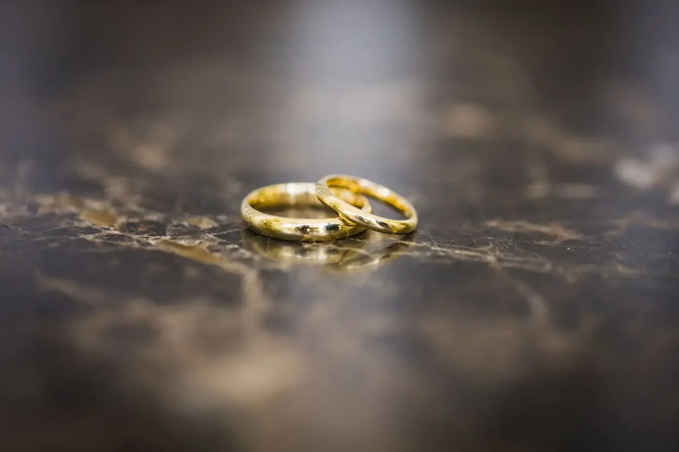 Close-up of elegant gold wedding rings on a polished marble surface, symbolizing marriage and love.