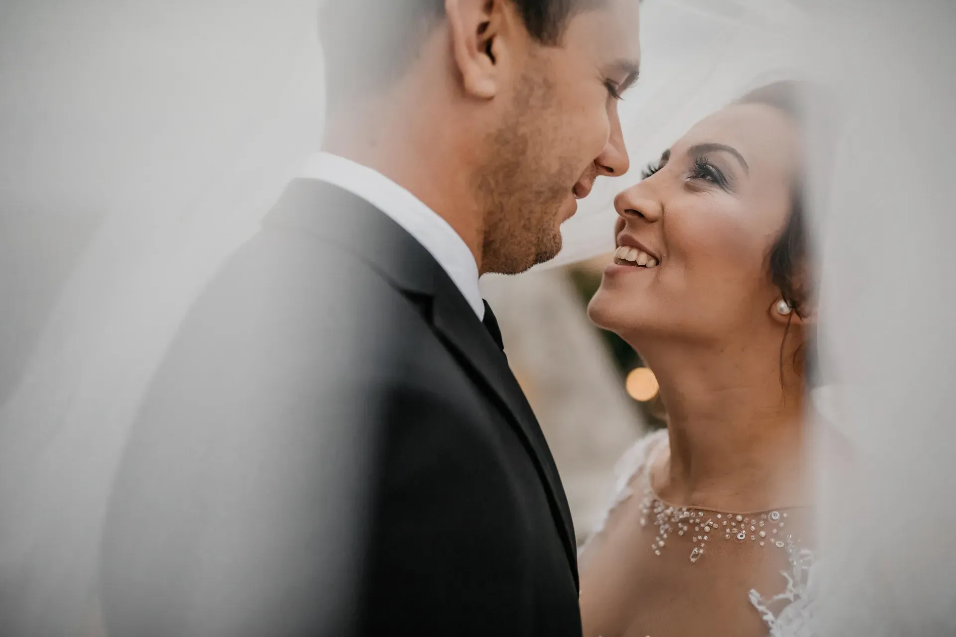 A couple photographed against a plain wall in north light.